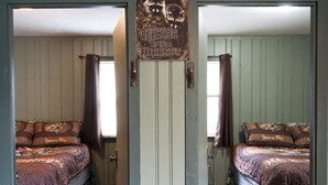 Una habitación con dos camas, una puerta con un cartel y suelo de madera.