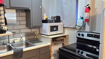 Une cuisine de taille réduite équipée d’un four à micro-ondes, d’une cuisinière et d’un évier.