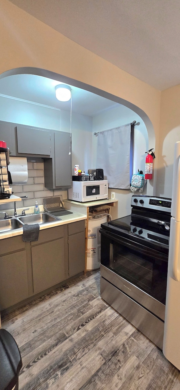 Una cocina compacta con microondas, estufa y lavabo.