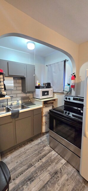 A compact kitchen with a microwave, stove, and sink.