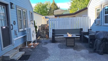 Un jardin avec un foyer, du mobilier d’extérieur et un barbecue abrité.