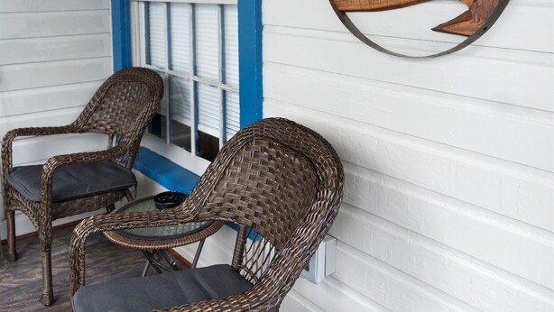 Un porche con sillas de mimbre y un letrero que dice "KCD Cozy Cottages".