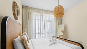 Ein Hotelzimmer mit einem großen Bett, einem Rattan-Kopfschild, einer hängenden Rattan-Leuchte und transparenten Vorhängen.