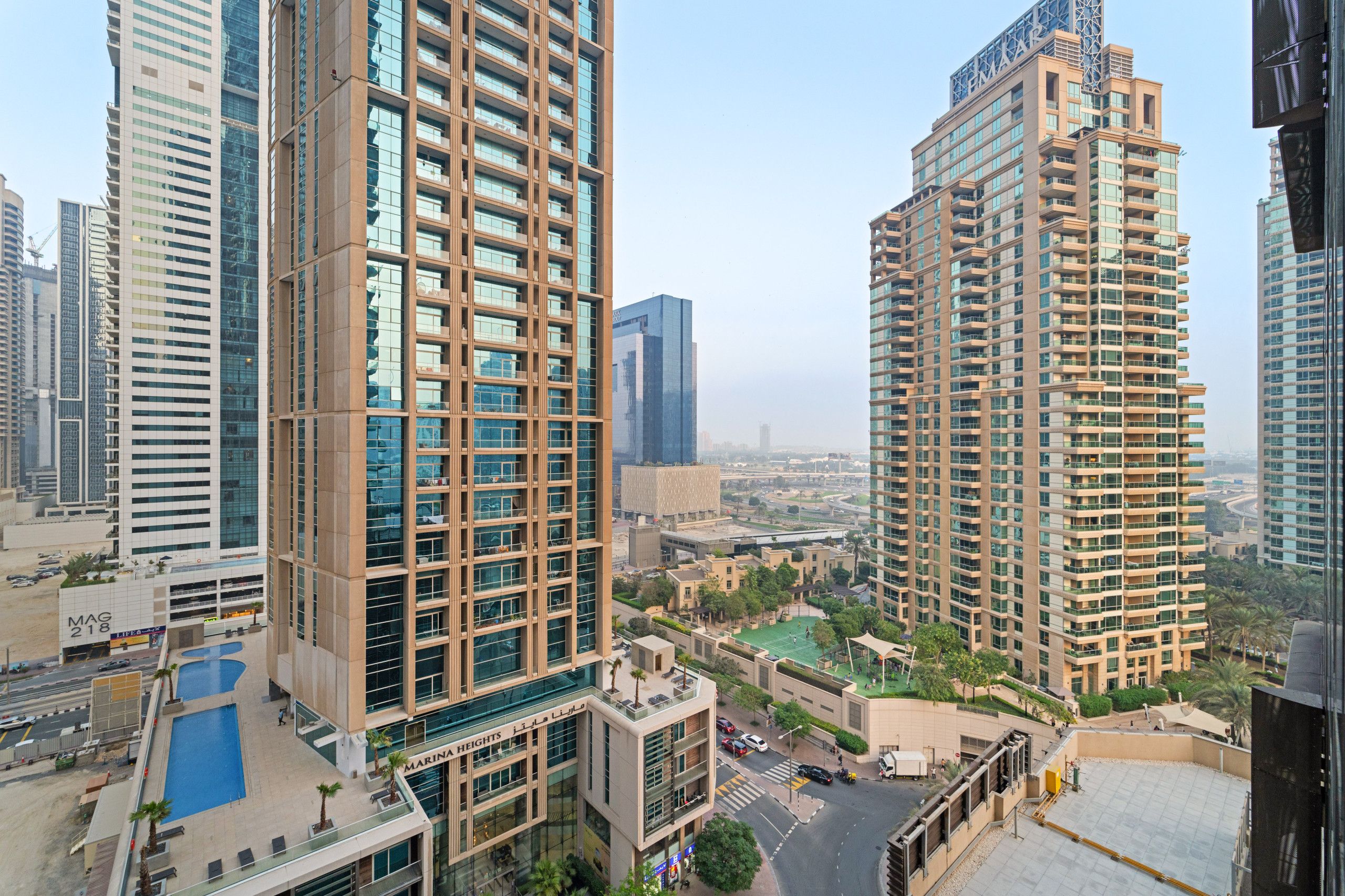 A high-rise building with multiple floors, large windows, and a rooftop area with a swimming pool.