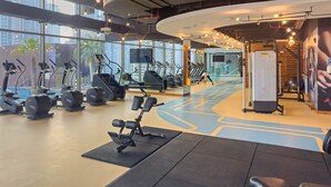 Ein Fitnessstudio mit Trainingsgeräten, großen Fenstern und modernem Design.