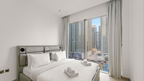 Ein modernes Hotelzimmer mit einem großen Bett, weißen Leinentüchern und Blick auf hohe Gebäude.