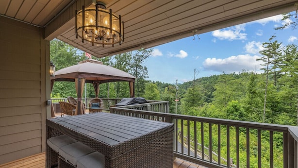 Une terrasse extérieure couverte, équipée d’une table et de chaises, d’un barbecue et d’un auvent.