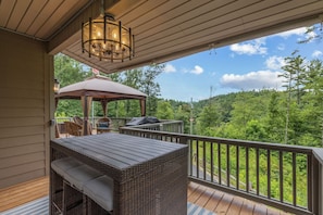 A covered outdoor deck with a table and chairs, a grill, and a canopy. - Lake access with mountain views! (Cullowhee)