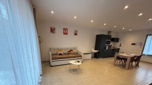 Ein modernes Wohnzimmer mit Sofa, Esstisch und Küchenzeile.