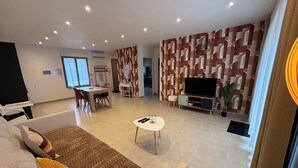 Ein modernes Wohnzimmer mit Sofa, Couchtisch, Fernseher und Wandverkleidung mit Muster.