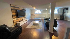 A modern living room with a flat-screen TV, wooden flooring, a sectional sofa, and a fireplace.