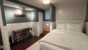 A bedroom with a bed, a desk, and a chair.