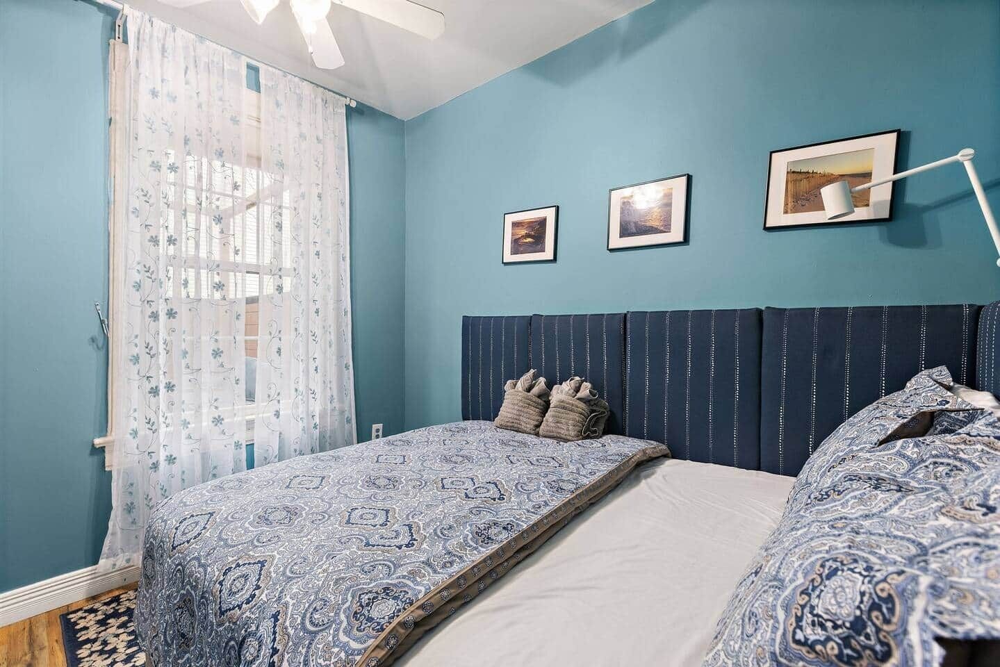 Un dormitorio con una cama, un ventilador de techo y tres cuadros en la pared.