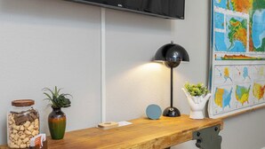 A wooden desk with a jar of cookies, a small plant, a lamp, and a white vase with a plant. - Gypsy Essence: Free Parking | Steps to Downtown (Eureka Springs)