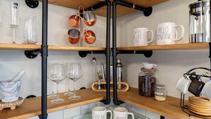 A kitchen with wooden shelves, copper cookware, and white mugs with text.