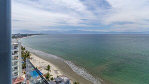 Une vue côtière avec une plage, l’océan et des montagnes à l’horizon.