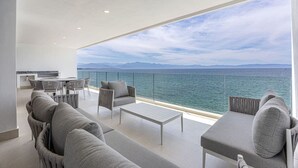 Un balcon moderne offrant une vue sur la mer et les montagnes.