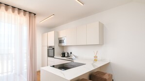 A modern kitchen with a central island, built-in appliances, and a large window with sheer curtains. - Apartment 'Maso Renner 8' with Mountain View, Wi-Fi and Air Conditioning (Laives)