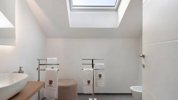 Une salle de bain moderne dotée d’un puits de lumière, d’un grand lavabo, de toilettes et d’un porte-serviettes.