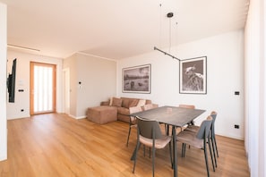 Una sala moderna con comedor, un sofá y dos cuadros en la pared.