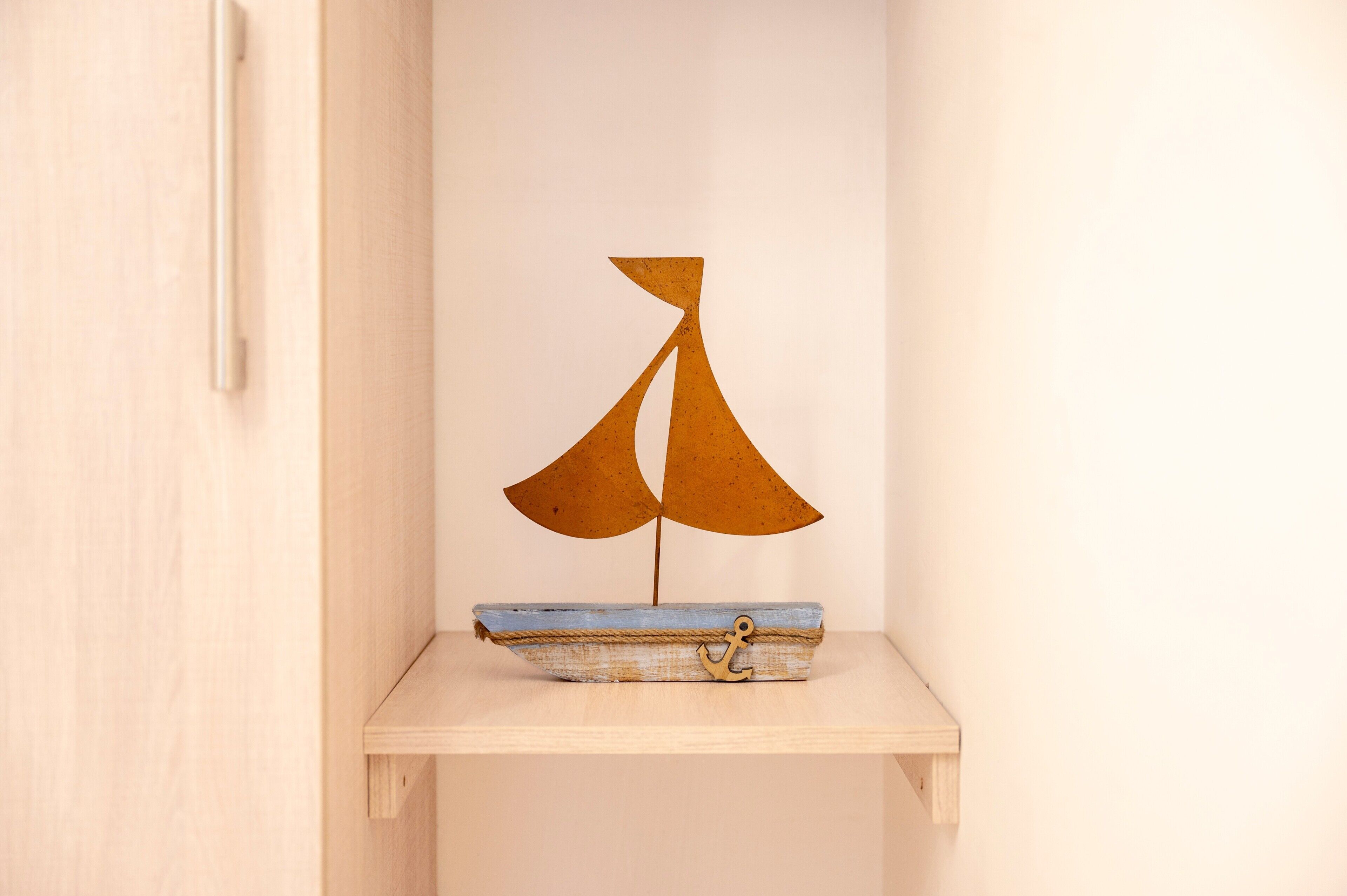 A small wooden shelf with a rustic sailboat model.