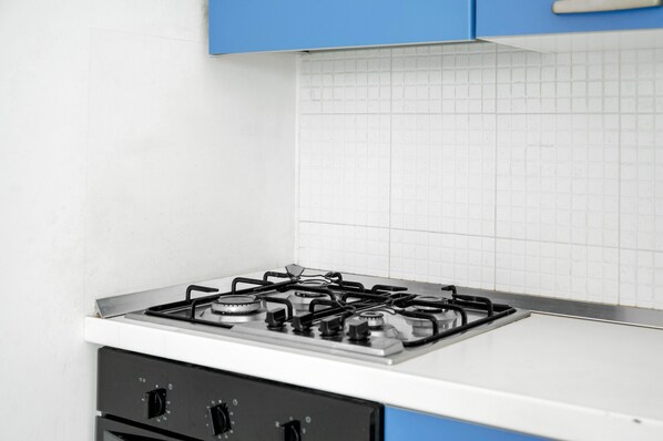 A kitchen with a gas stove, white tiled backsplash, and blue cabinets. - Apartment 'Apt 5' with Shared Terrace, Wi-Fi and Air Conditioning (Otranto)