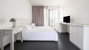 A hotel room with a bed, a desk, a television, and a balcony.