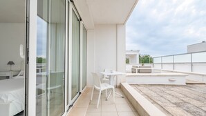 A modern hotel room with a balcony, a bed, a desk, and a chair.
