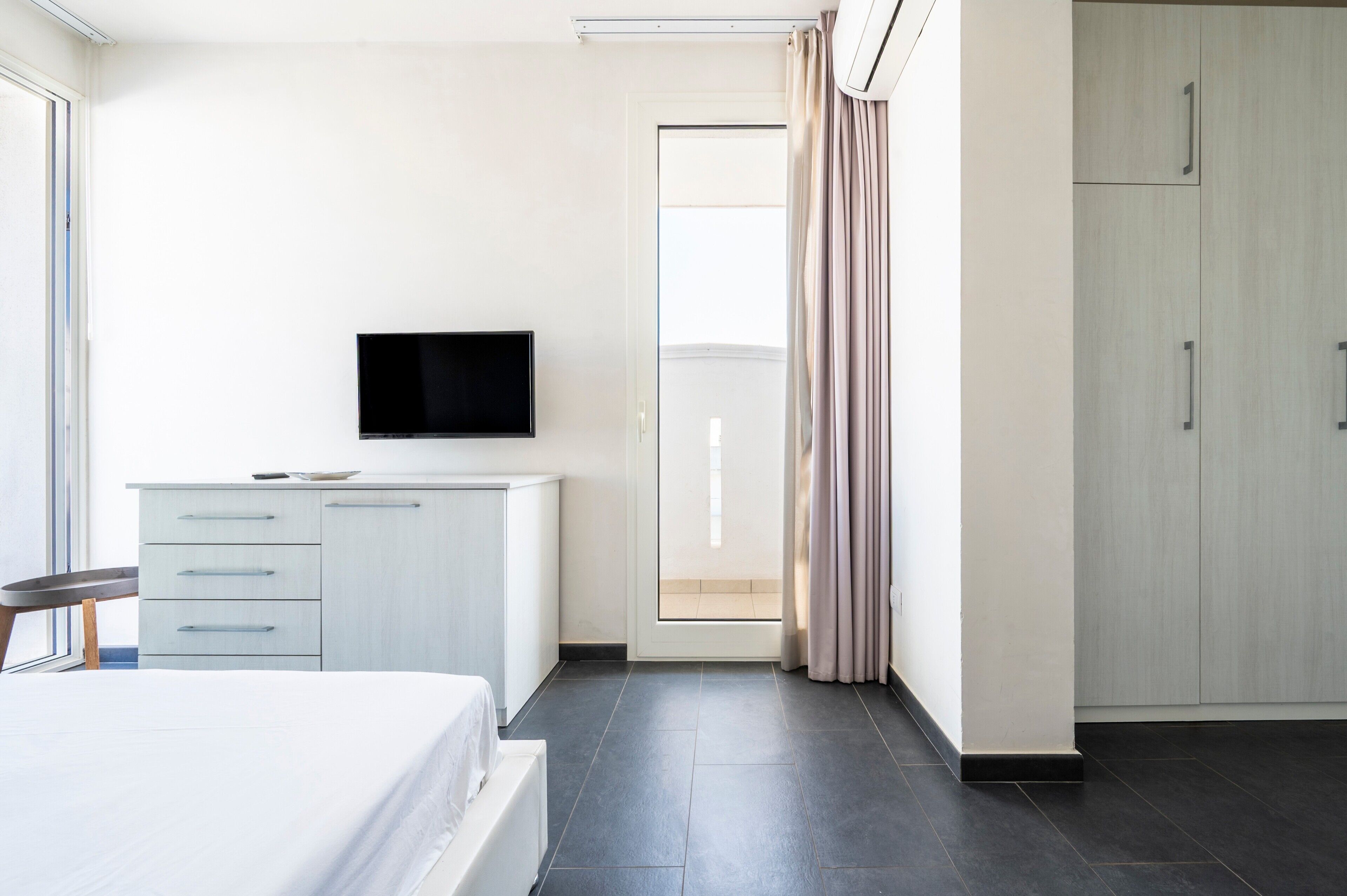 A hotel room with a bed, a TV, a desk, and a wardrobe.
