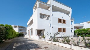 Un moderno edificio blanco con balcones, una escalera y plantas en macetas.