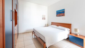 Une chambre à coucher comprenant un lit, une table de chevet, une lampe, un tableau accroché au mur et une armoire.
