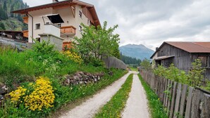 Une route de campagne bordée de maisons, d’un mur de pierre et d’une clôture en bois.