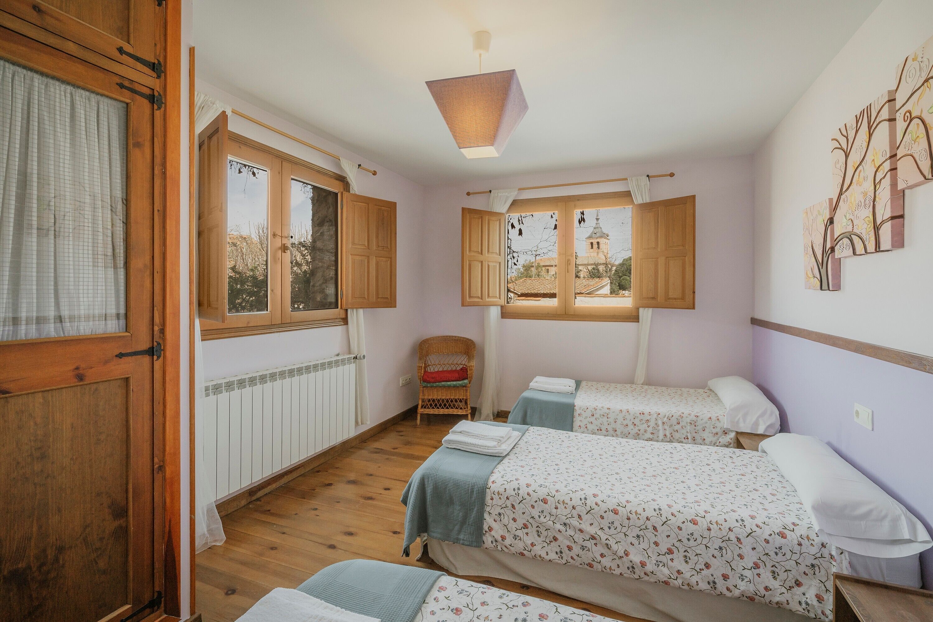 Una habitación con dos camas, una ventana, una silla y un radiador.