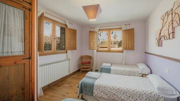 Una habitación con dos camas, una ventana, una silla y un radiador.