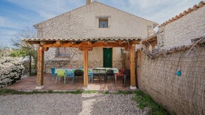 A stone house with a covered patio, a green door, and a small window. - Holiday Home 'La Alameda' with Private Pool, Garden, BBQ & Wi-Fi (MARAZUELA)
