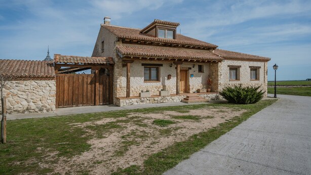 A two-story stone house with a tiled roof, a wooden gate, and a paved driveway. - Holiday Home 'La Alameda' with Private Pool, Garden, BBQ & Wi-Fi (MARAZUELA)