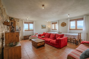 Un salon avec un canapé rouge, une table basse en bois et un coin repas comprenant une table et des chaises.