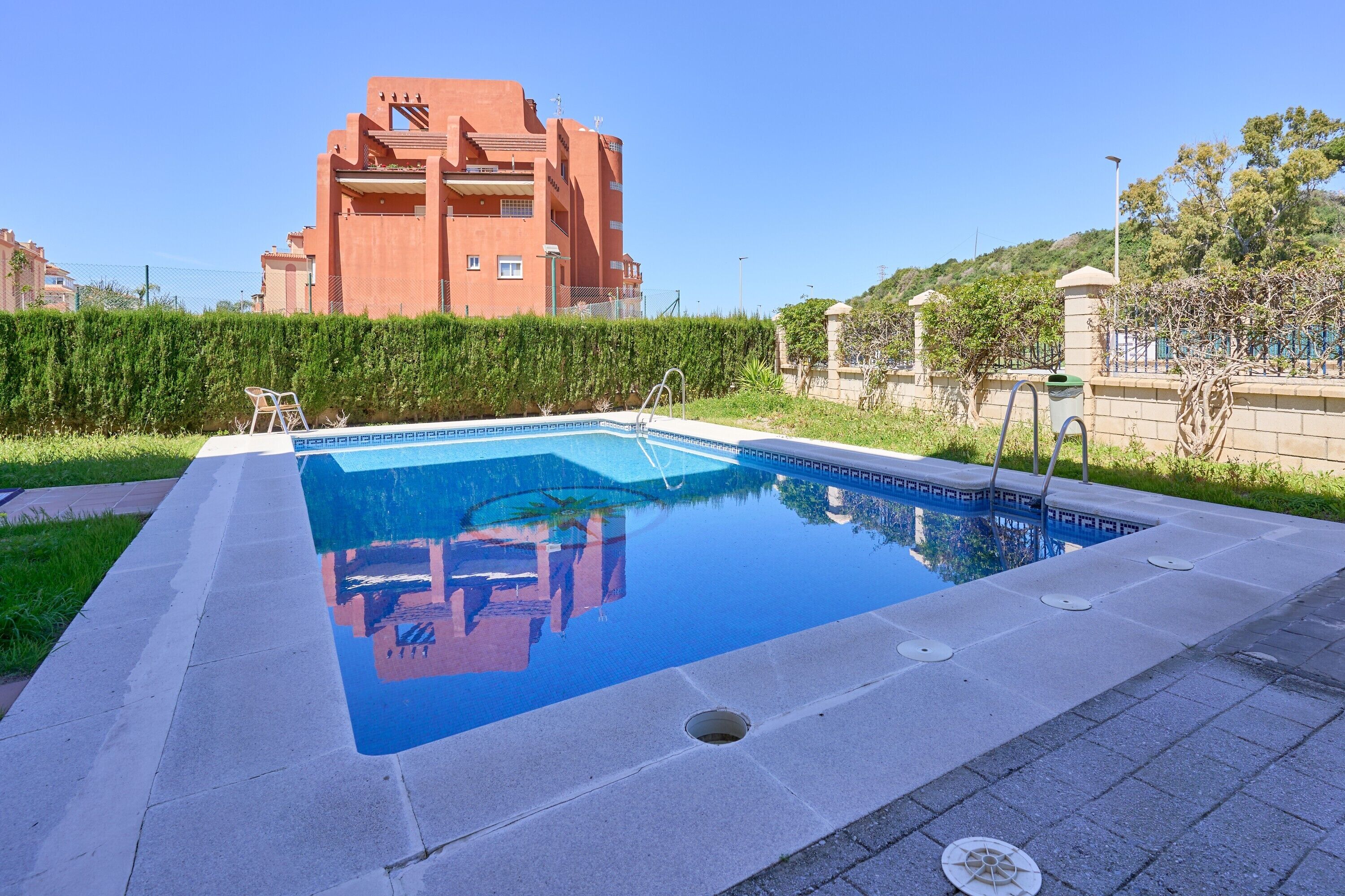 Una piscina rectangular con superficie de agua azul cristalina, rodeada por una solana pavimentada.
