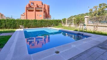Una piscina rectangular con superficie de agua azul cristalina, rodeada por una solana pavimentada.