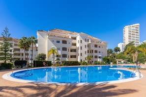 Ein Hotel mit Schwimmbad, Palmen und blauem Himmel.