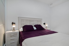 Un dormitorio con una cama, dos mesitas de noche y un cabecero.