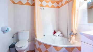 Un baño con inodoro, bañera y cortina de ducha.