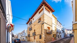 A narrow street with stone buildings, a parked car, and a clear blue sky. - Country House 'Virginia' with Mountain View and Balcony (Unknown)
