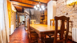 A dining area with a wooden table and chairs, stone walls, a chandelier, and a staircase leading to an upper level. - Country House 'Virginia' with Mountain View and Balcony (Unknown)
