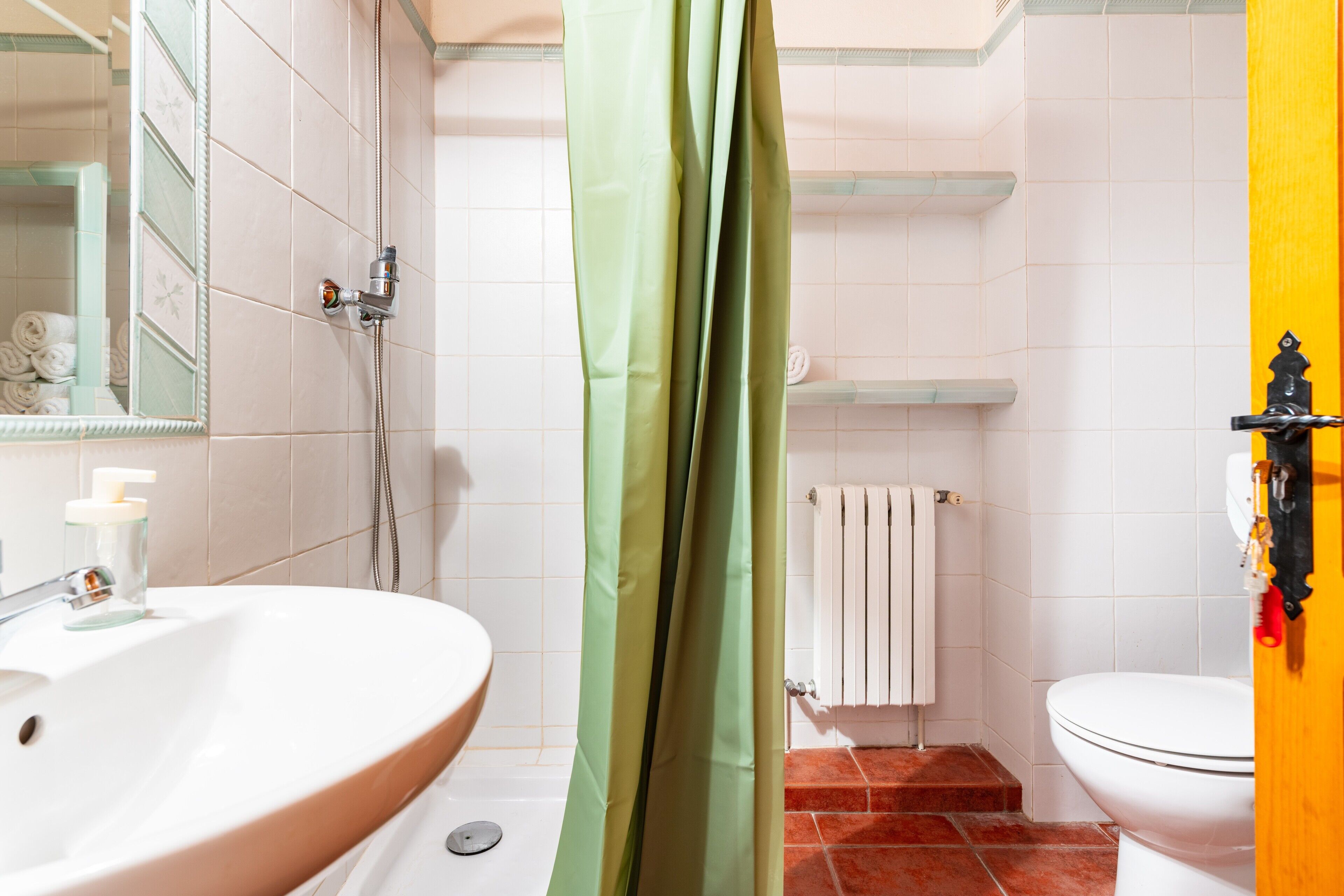 Un baño con lavabo, ducha, inodoro y espejo.