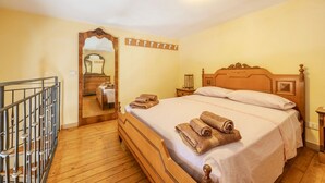 A bedroom with a wooden bed, a mirror, a nightstand, and a wall-mounted coat rack. - Holiday Home 'Zaami' with Sea View, Wi-Fi and Air Conditioning (Palermo)