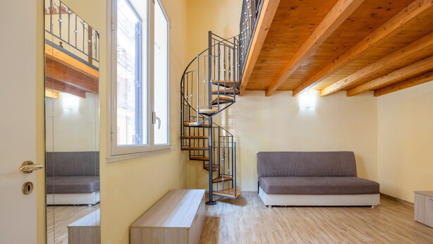 A modern interior with a spiral staircase, a grey sofa, and wooden flooring. - Holiday Home 'Zaami' with Sea View, Wi-Fi and Air Conditioning (Palermo)