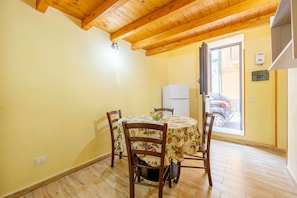 A dining area with a round table, four chairs, and a ceiling with wooden beams. - Holiday Home 'Zaami' with Sea View, Wi-Fi and Air Conditioning (Palermo)