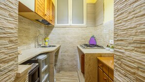 A compact kitchen with a built-in stove, a sink, and wooden cabinets. - Holiday Home 'Zaami' with Sea View, Wi-Fi and Air Conditioning (Palermo)