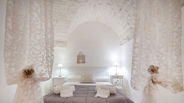 Een slaapkamer met een bed, twee nachtkastjes, en een wandlamp.